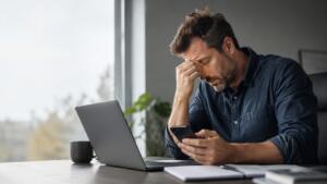Erschöpfte Person nimmt Burnout-Symptome am Arbeitsplatz wahr.